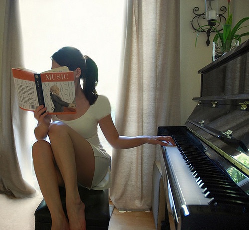 Загорелая сексуальная пианистка позирует у рояля 